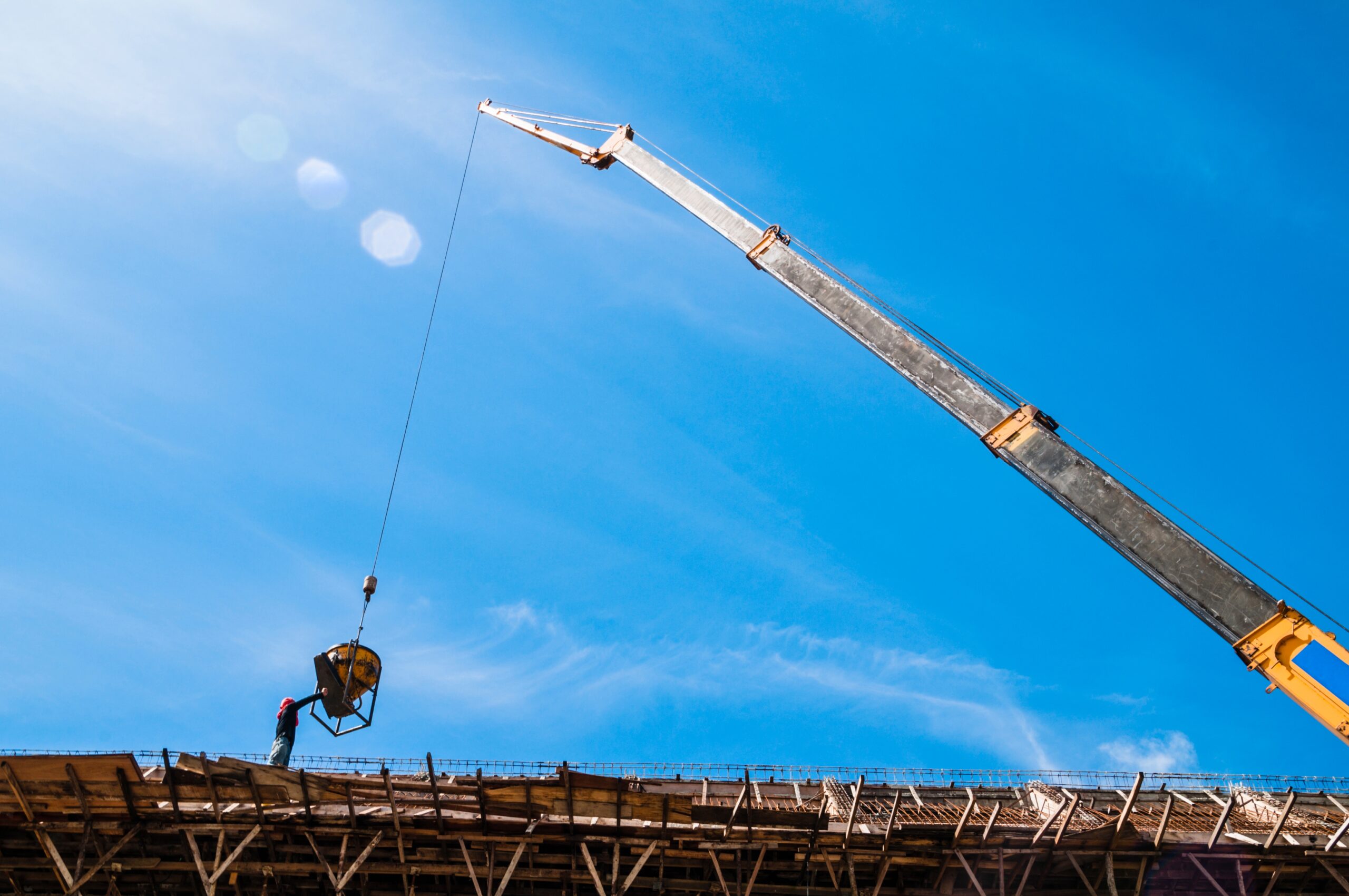 Crane lifting a bucket of cement at construction site